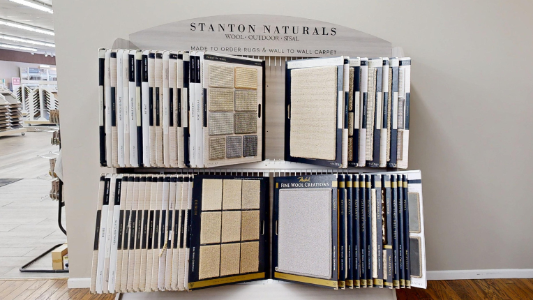 Display of Stanton Naturals carpet samples, featuring various textures and colors, with a sign indicating 